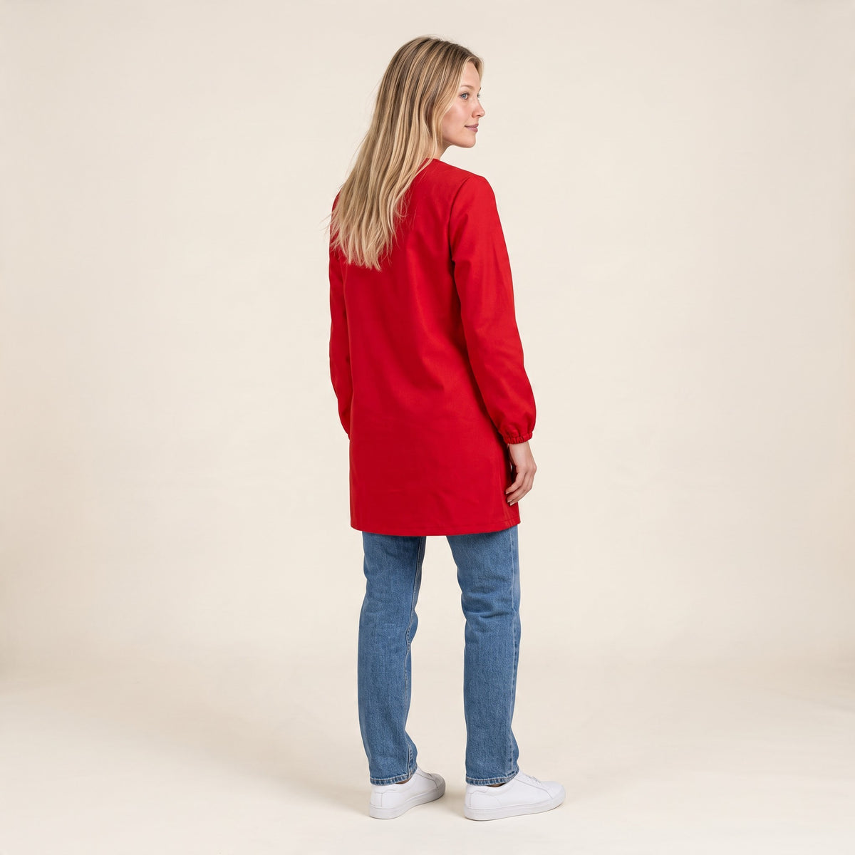 Bata escolar roja de SuYa Shop con puños elásticos, vista trasera de una mujer con vaqueros y zapatillas blancas