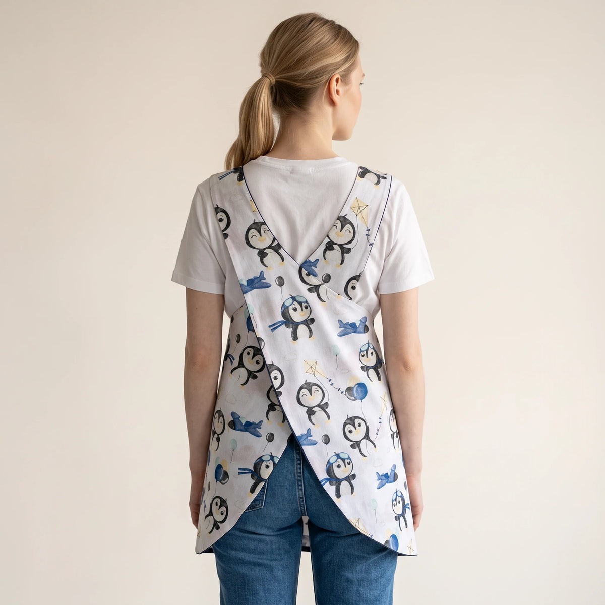 Bata de professora SuYa Shop com estampado de pinguins, costas cruzadas, sobre t-shirt branca e calças de ganga