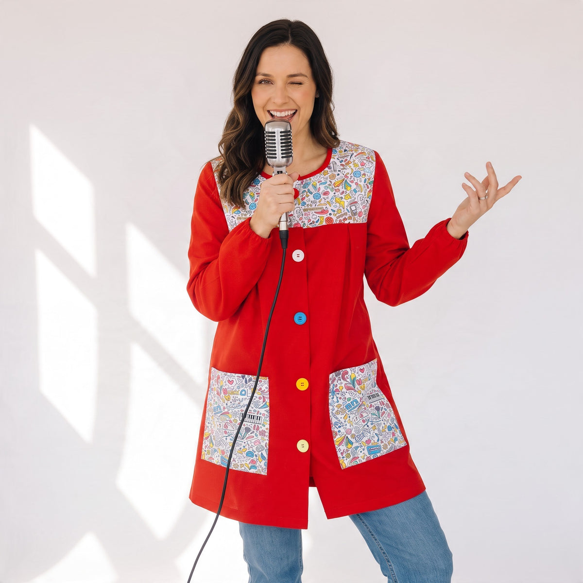 Bata de maestra SuYa Shop roja de manga larga con estampado musical y botones de colores sobre fondo blanco