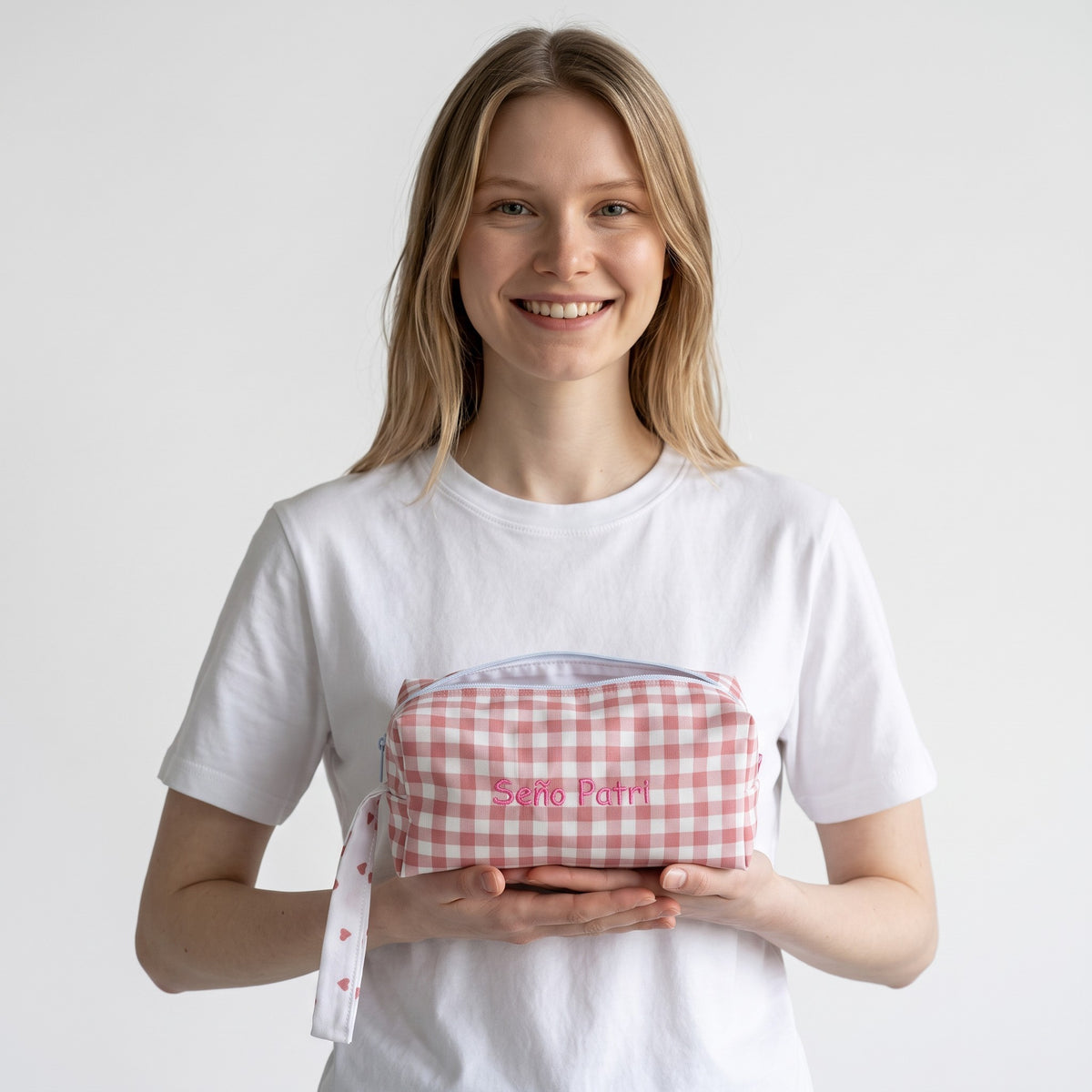 Donna sorridente che tiene un astuccio SuYa Shop maxi con quadretti vichy rosa e ricamo personalizzato.