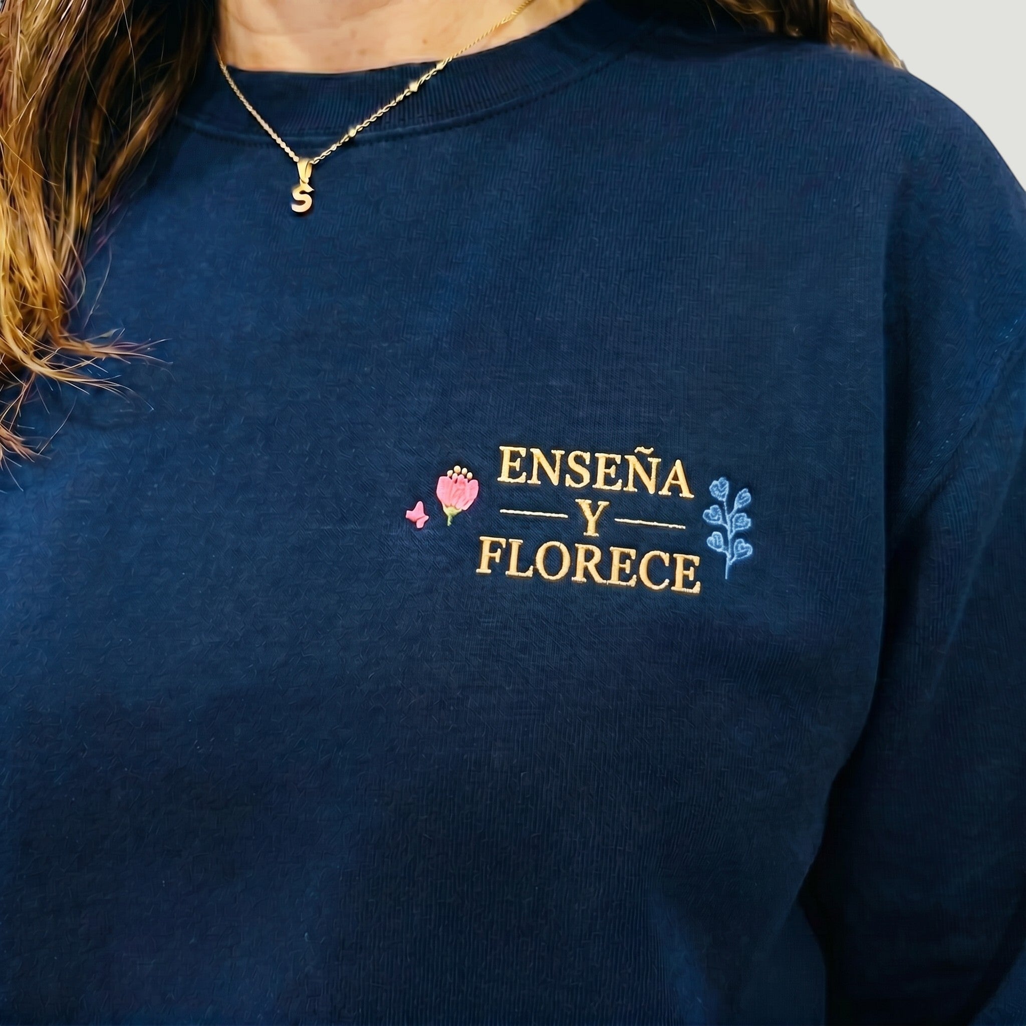 SuYa Shop navy blue sweatshirt for teachers with Enseña y Florece floral embroidery on the chest.