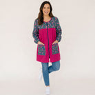 Mujer sonriente vistiendo bata SuYa Shop de manga larga con estampado floral y detalles en color fucsia vibrante