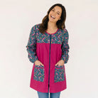 Mujer sonriente vistiendo bata SuYa Shop de manga larga en color fucsia con estampado floral en bolsillos y hombros
