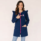 Mujer sonriente vistiendo bata azul marino SuYa Shop con cremallera rosa, volantes en hombros y letra personalizada