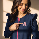 Mujer sonriente vistiendo bata azul marino SuYa Shop con cremallera rosa y detalle de letra A bordada