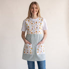 Bata de maestra SuYa Shop con estampado de margaritas y abejas sobre fondo de cuadros vichy verde y blanco