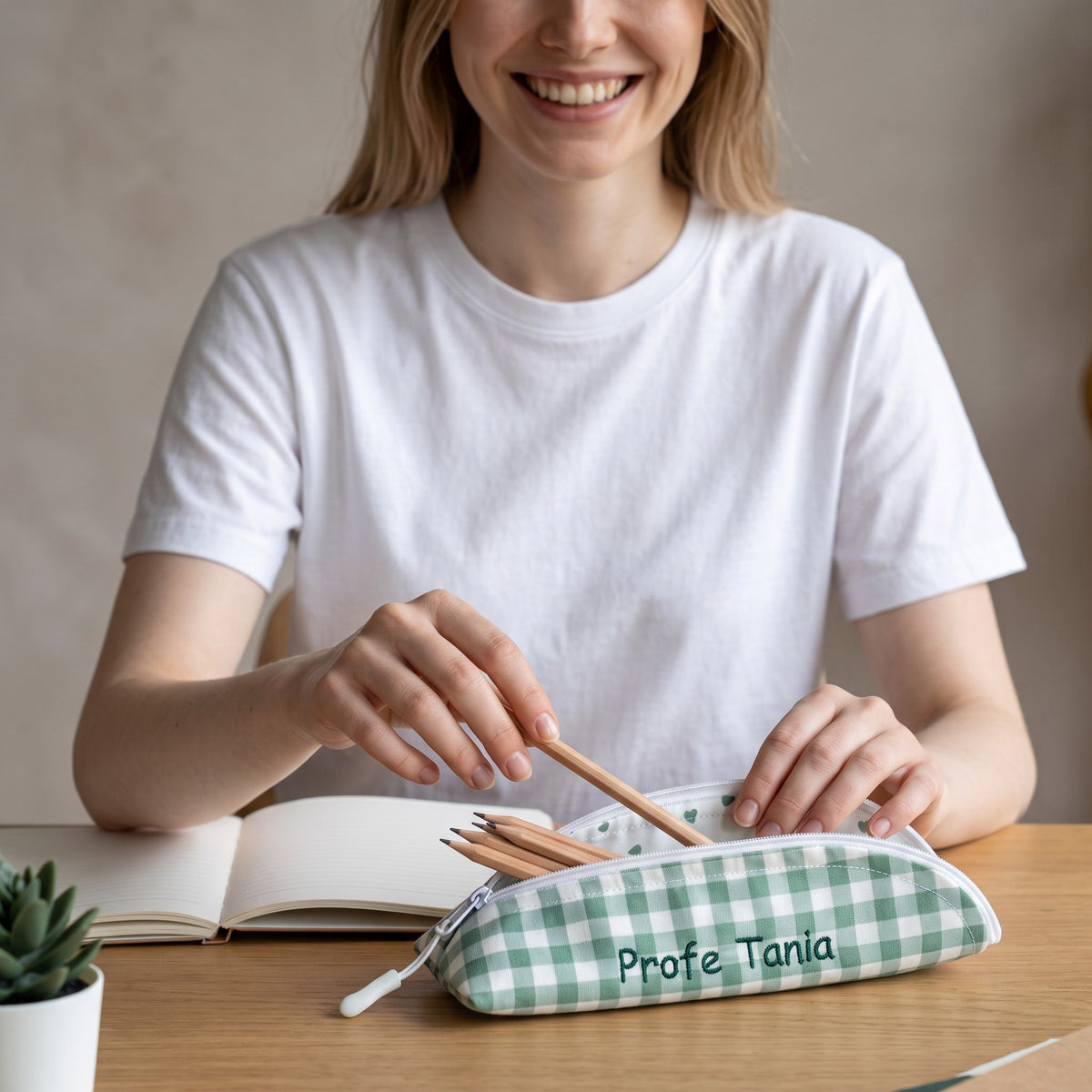 Astuccio SuYa Shop con quadretti vichy verdi e cuori, personalizzato per la maestra, su un tavolo di legno