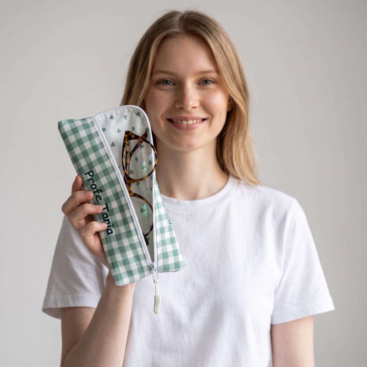 Donna che tiene un astuccio SuYa Shop in tessuto con stampa vichy verde e cuori, ideale per matite o occhiali.