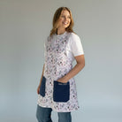 SuYa Shop floral print teacher apron with navy blue pockets worn by a smiling woman