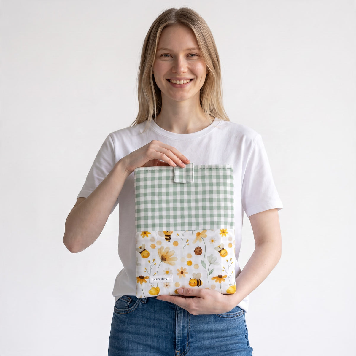 Mujer sonriente sosteniendo una funda acolchada SuYa Shop con estampado de abejas y flores y parte superior de cuadros