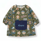 SuYa Shop infant school smock in olive green with sports print, elastic cuffs, and a navy blue personalized pocket.