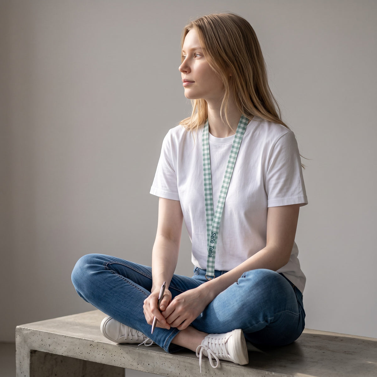 Giovane donna seduta con lanyard SuYa Shop a quadretti verdi e bianchi per chiavi o badge