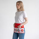 Mulher a usar um avental de Natal vermelho da SuYa Shop com estampado de casas com neve e bolsos frontais