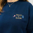SuYa Shop navy blue sweatshirt featuring Teach and Bloom floral embroidery on the chest for teachers.