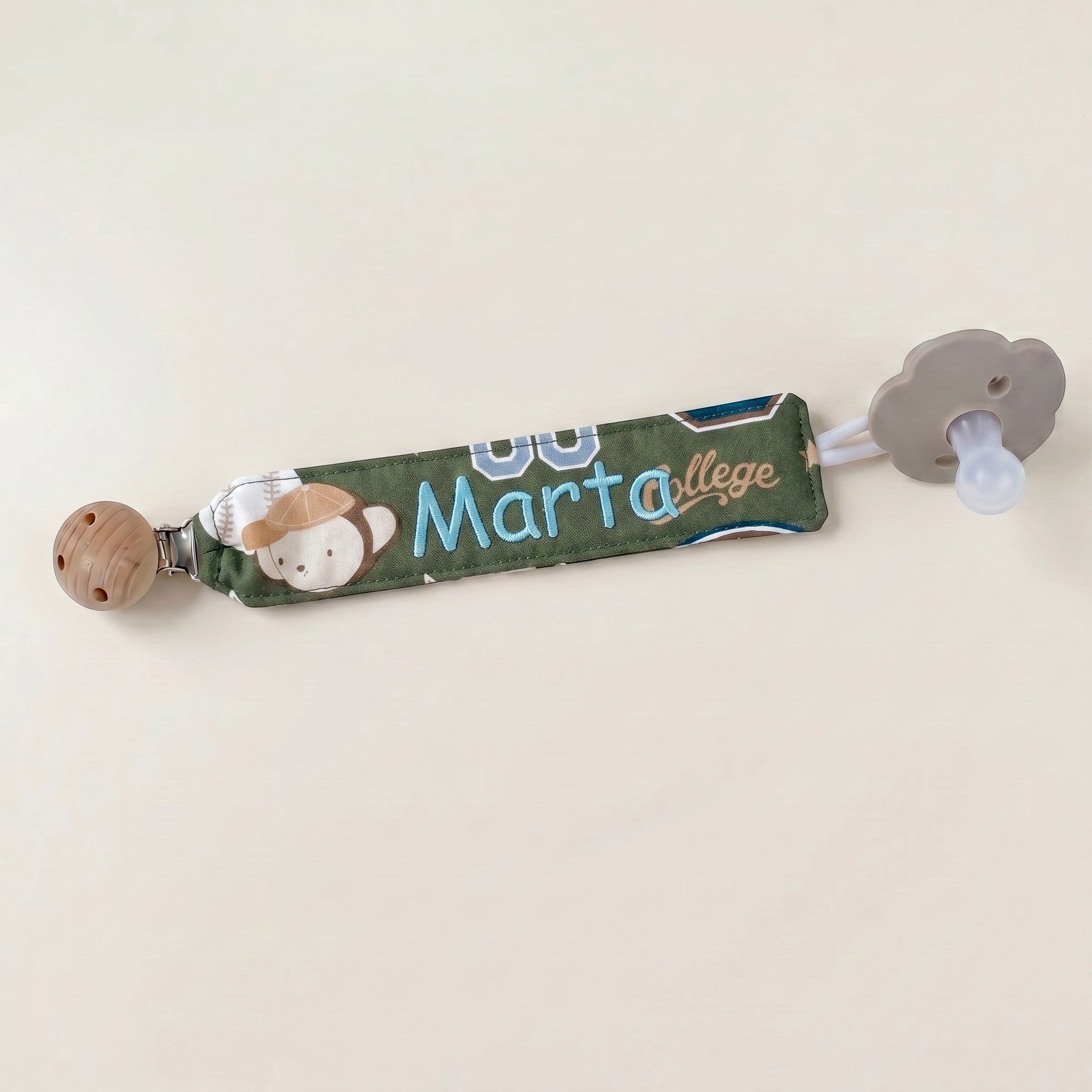 SuYa Shop personalized green fabric pacifier clip featuring a cute monkey design and the name Marta embroidered