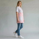 SuYa Shop teacher smock in pink with floral pattern, sleeveless design, and large pockets, worn by a smiling woman.