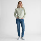 Modelo sorridente com sweatshirt SuYa Shop cor de menta, inicial em estampado vichy e calças de ganga azuis