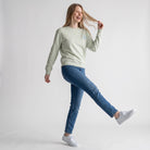 Modelo sorridente a usar uma sweatshirt SuYa Shop cor de menta com inicial em estampado vichy e calças de ganga azuis