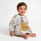 SuYa Shop toddler school smock with animal print, elastic cuffs, and personalized pocket on a smiling baby
