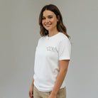 SuYa Shop white cotton t-shirt for teachers with Teach and Bloom embroidery on a smiling woman